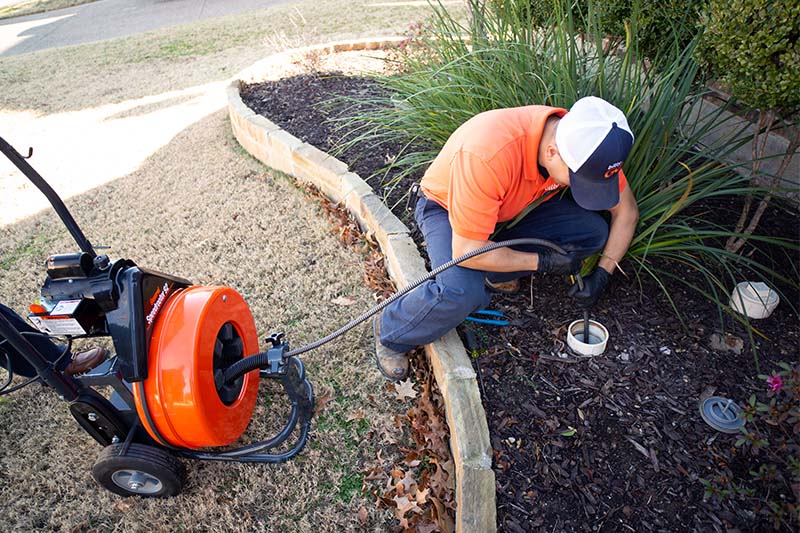 Sewer Pipe Cleaning using a plumbing snake outside a home in Dallas-Forth Worth